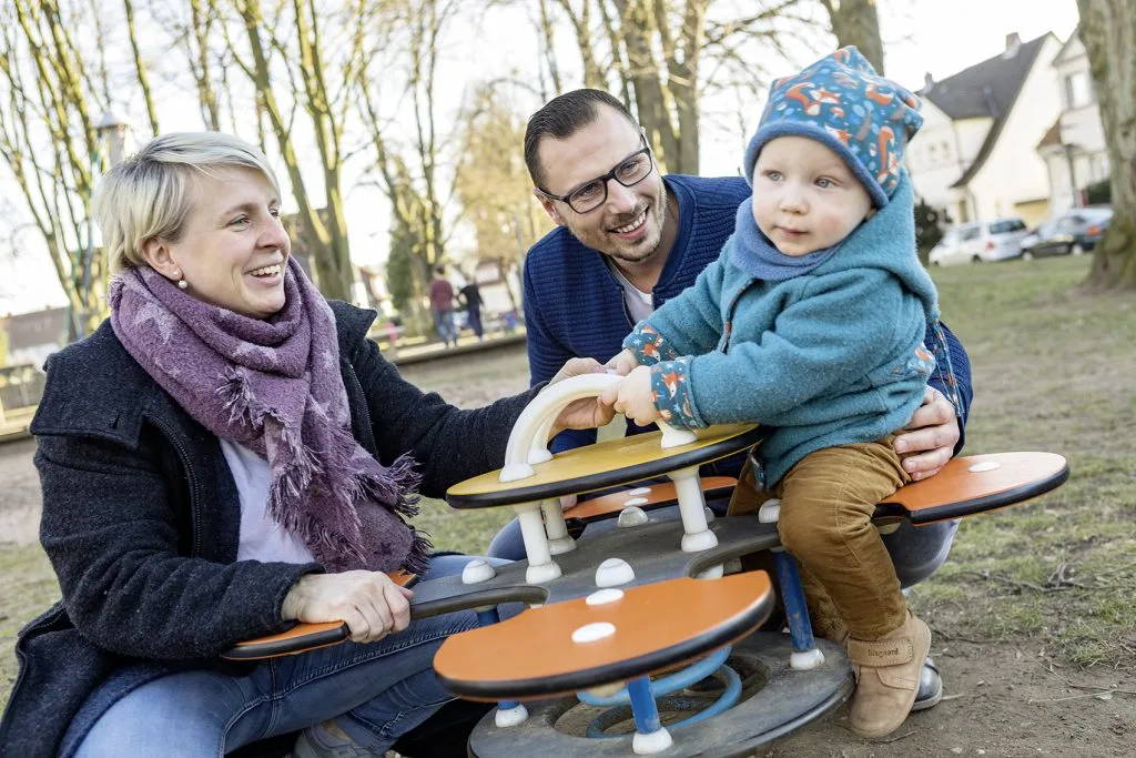 Eltern mit Kind auf Spielplatz V